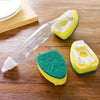 A dish wand cleaning brush set featuring a yellow and green sponge with a clear handle on a wooden surface.