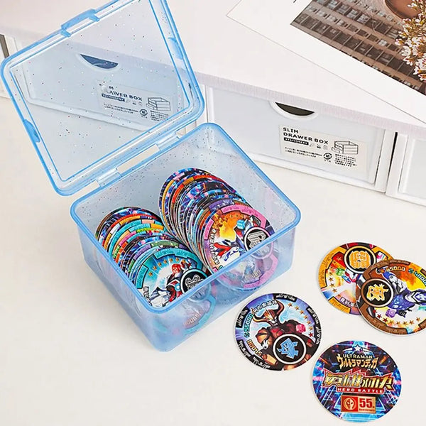 A clear plastic storage box filled with colorful circular items, displayed next to a white drawer box.