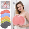 A woman holds a pink reusable silicone foot scrub brush, showing its texture and shape.