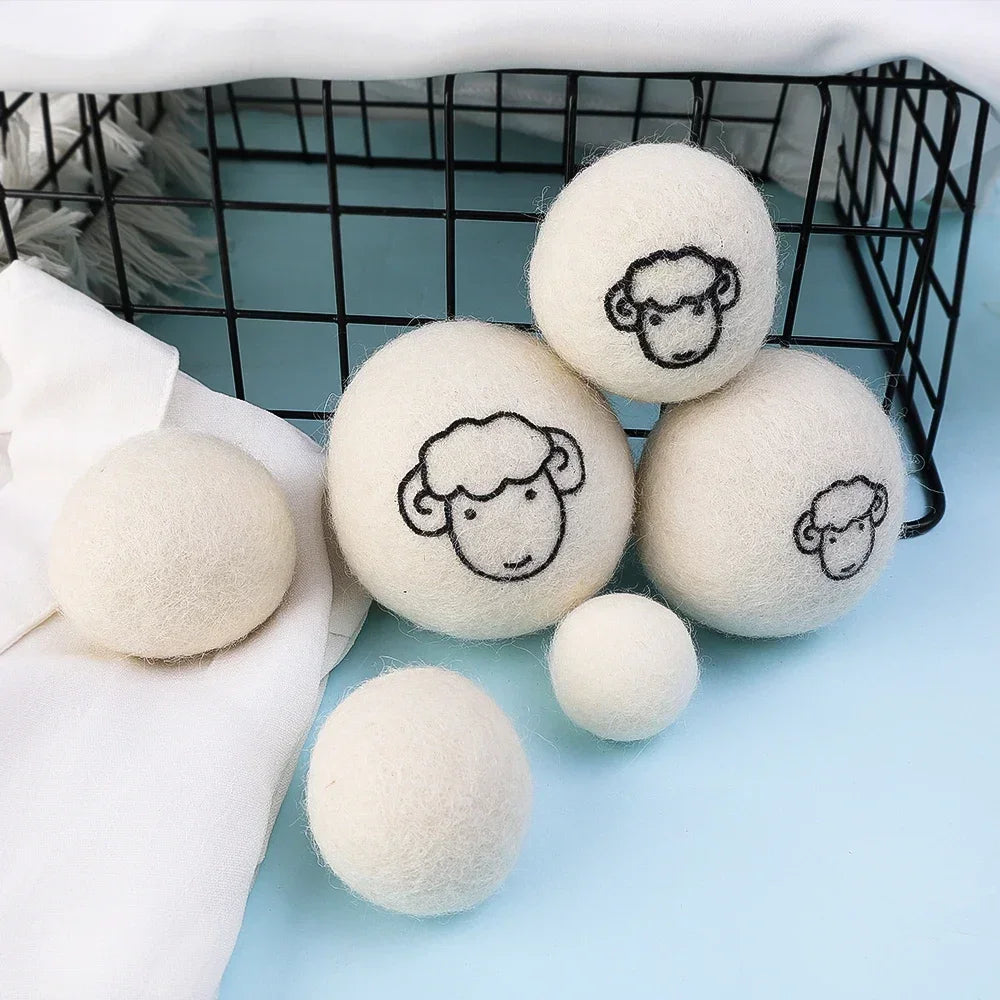 A set of six white wool dryer balls are displayed in a black wire basket on a light blue surface.