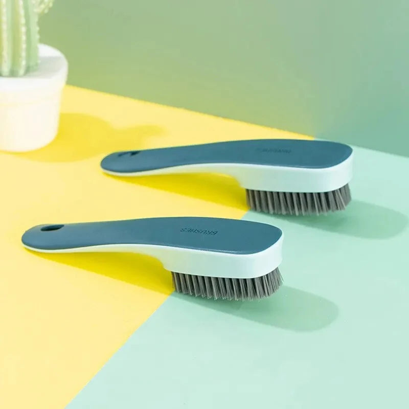 Une paire de brosses multifonctionnelles pour nettoyer des chaussures et des vêtements bleues et blanches, posées sur une sur