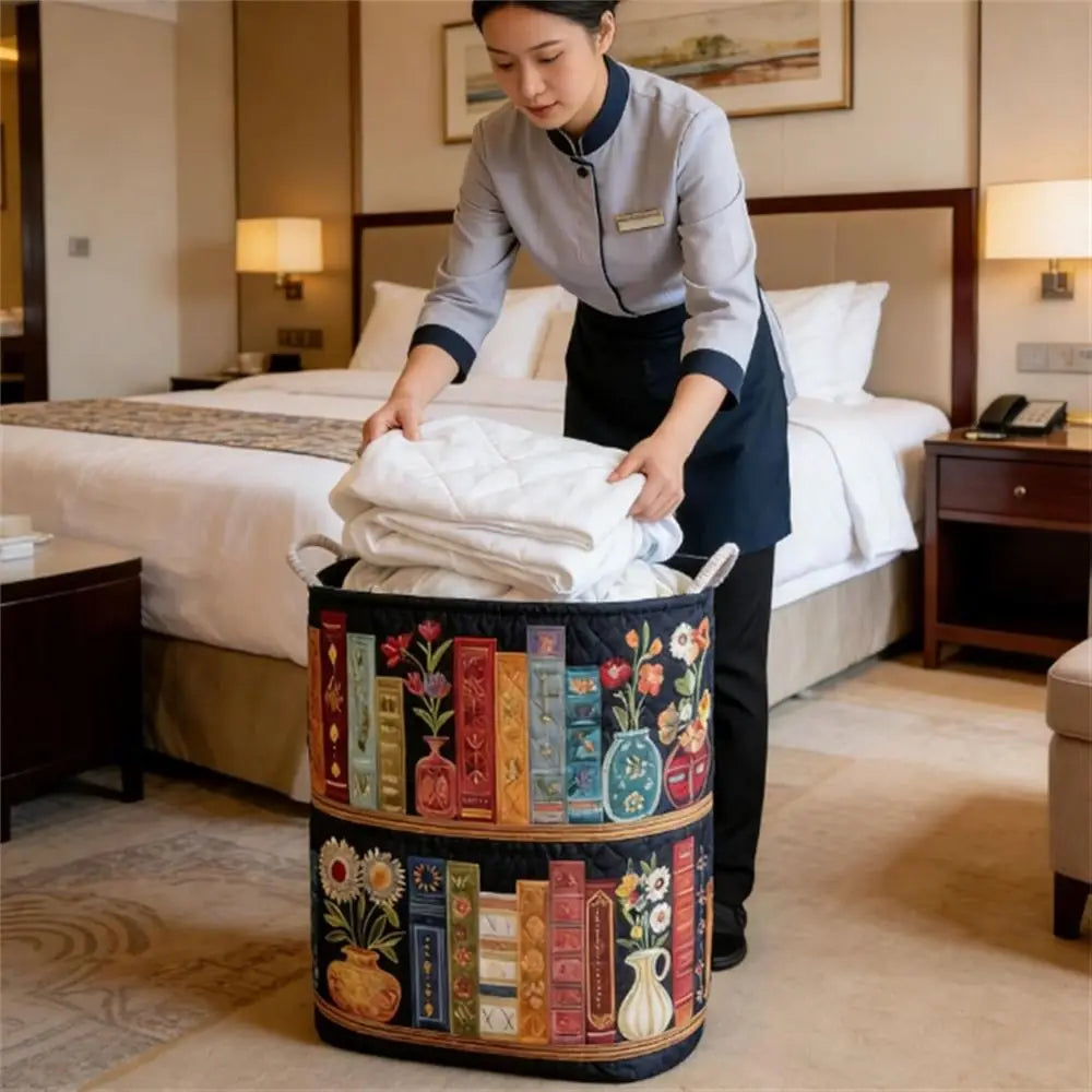 A woman is placing neatly folded white towels into a floral patterned fabric laundry basket in a bedroom setting.