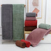A set of folded absorbent towels in various shades of gray, green, and pink are displayed on a shelf.