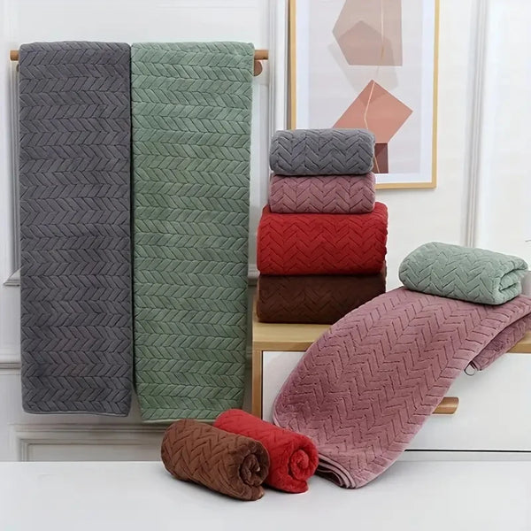 A set of folded absorbent towels in various shades of gray, green, and pink are displayed on a shelf.