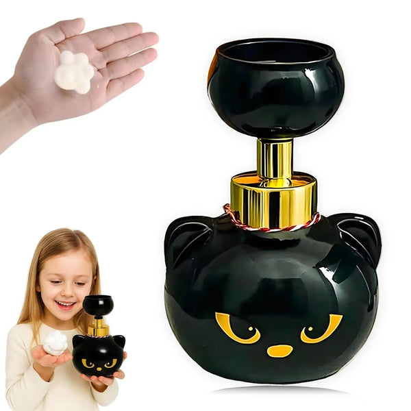 A black ceramic cat face soap dispenser with gold accents and a white foam paw is shown next to a child's hand.