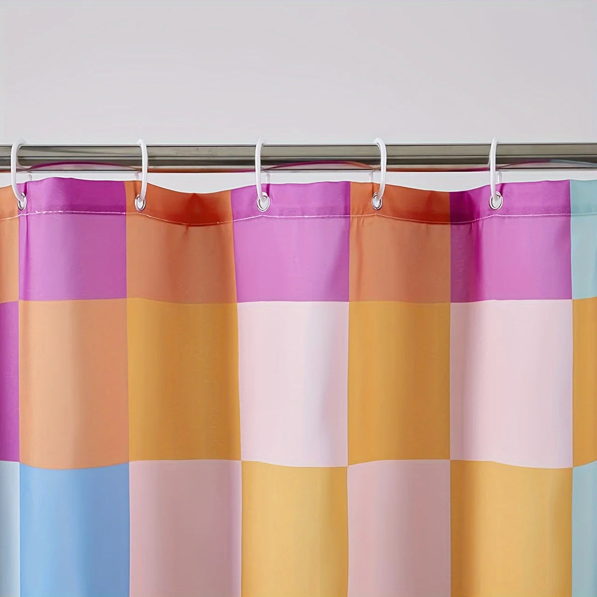 Cortina de ducha retro y colorida con diseño de patchwork en tonos morado, naranja, rosa y azul.