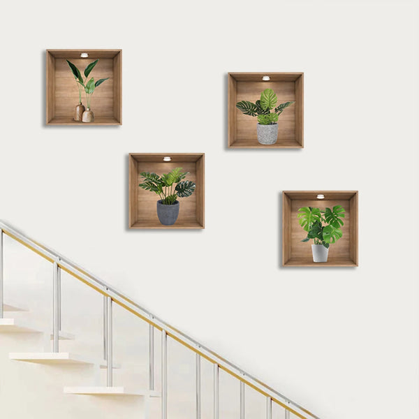 A gallery wall display featuring four potted green plants in wooden frames mounted on a white wall.