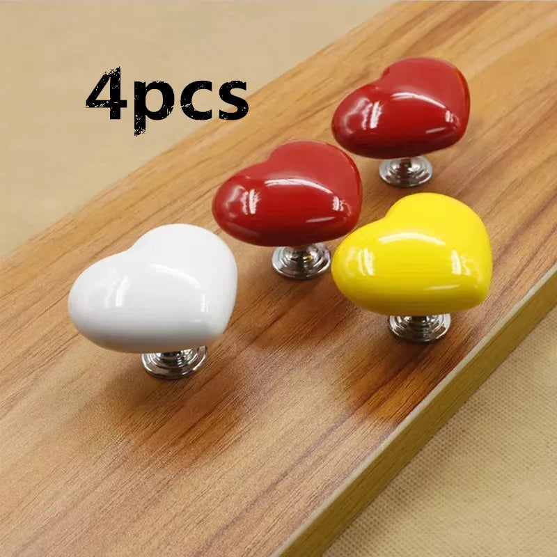 Boutons de chasse d'eau en forme de cœur rouges, jaunes et blancs sur une surface en bois.