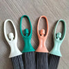 A set of mini broom and dustpan for desk cleaning, featuring light green and white handles and dark bristles.