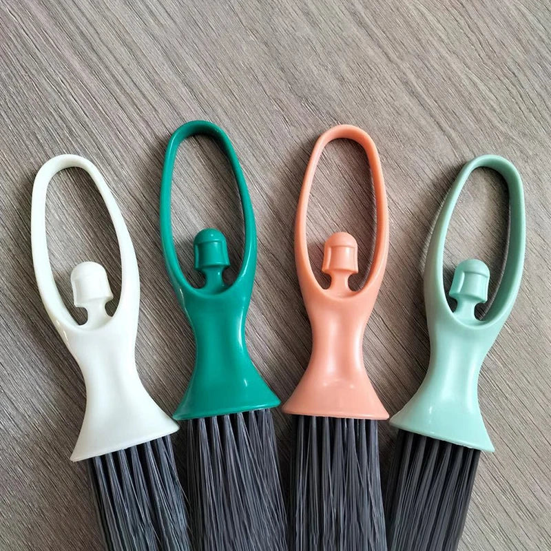 A set of mini broom and dustpan for desk cleaning, featuring light green and white handles and dark bristles.
