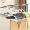 A rack of white plastic non-slip hangers with metal hooks is displayed on a yellow garment.
