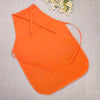 Orange non-woven craft apron laid flat on a light gray fabric with a small white flower in the background.