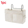 A beige fabric storage basket with a black hanging rack for bedside use.