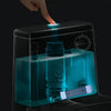 A hand is inserting a magnetic toilet cleaning stick into a clear plastic container for use.