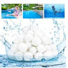 A pile of white eco-friendly pool filter cleaning balls submerged in blue water.