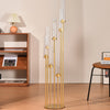 Centro de mesa de candelabro dorado alto con siete brazos delgados de vidrio sobre un suelo de madera.