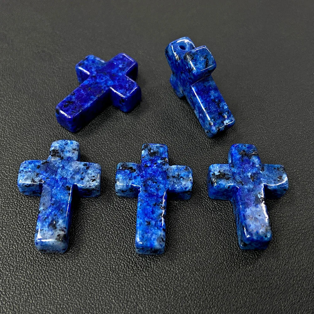 Three blue agate and jasper cross pendant charms displayed on a dark surface.