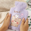 A hand is holding a purple plush cartoon bear hot water bottle with a pink flower design.