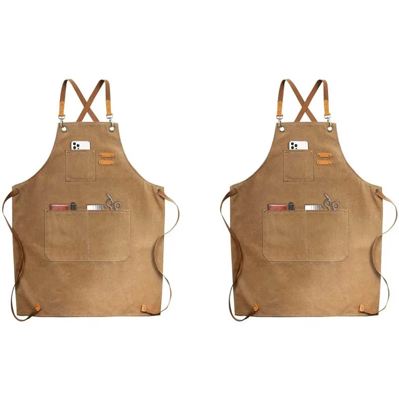 A tan canvas apron with utility pockets and crossed straps is shown against a white background.