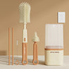 A set of silicone bottle brushes and a drying rack displayed on a light surface.