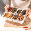 An 8 compartment snack organizer tray filled with various dried spices and herbs like chili peppers and seeds.
