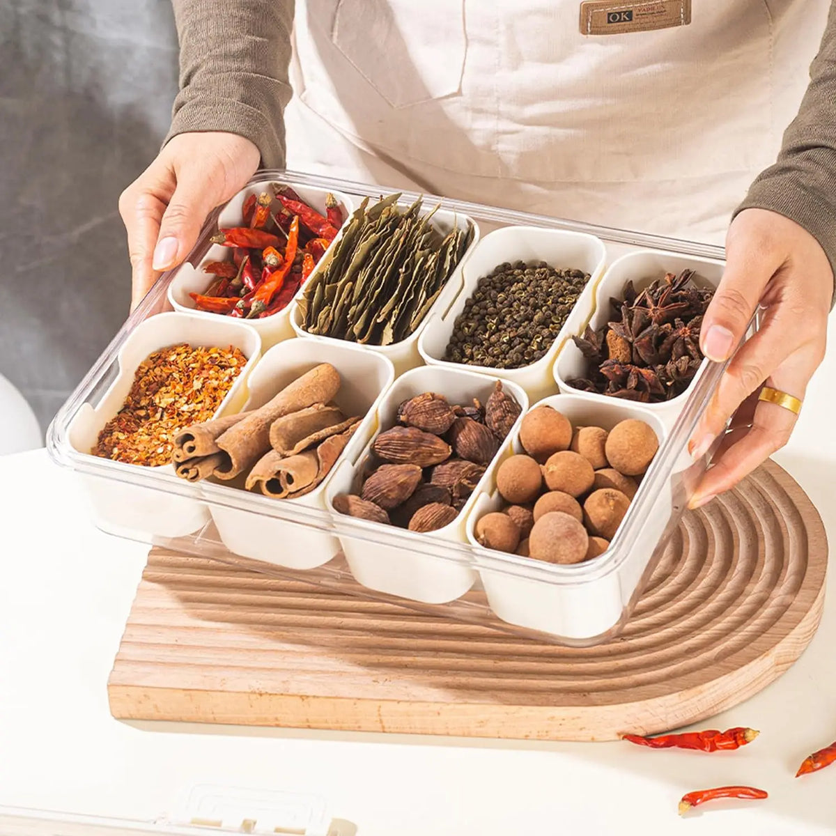 An 8 compartment snack organizer tray filled with various dried spices and herbs like chili peppers and seeds.