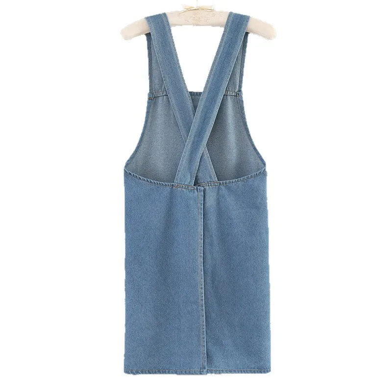 A denim apron with a V-neck and crossed straps is displayed on a hanger.