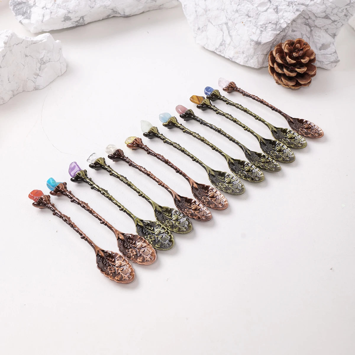 A row of natural crystal spoons with various colors and textures arranged on a white background.