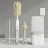 A set of silicone bottle brushes and a drying rack displayed on a light gray surface.