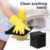 A hand wearing a yellow cleaning glove is wiping a stainless steel pan with a black microfiber cloth.