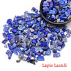 Una pila de vibrantes cristales de lapislázuli azul esparcidos sobre un fondo blanco con un tazón pequeño cerca.