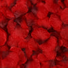 Primer plano de pétalos de rosa artificiales rojos y vibrantes esparcidos sobre una superficie.