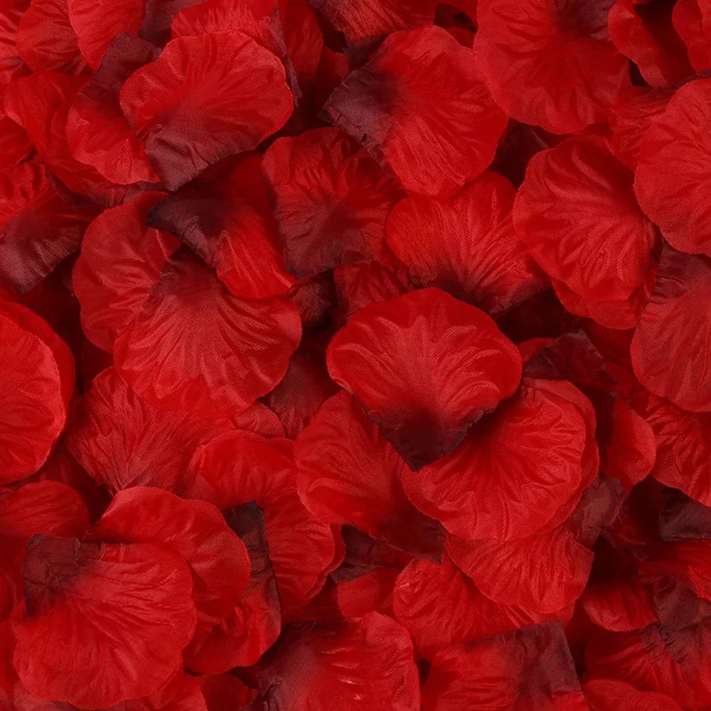 Primer plano de pétalos de rosa artificiales rojos y vibrantes esparcidos sobre una superficie.