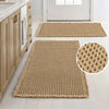 A rectangular beige waffle weave non-slip bathroom rug placed on a light wood floor.