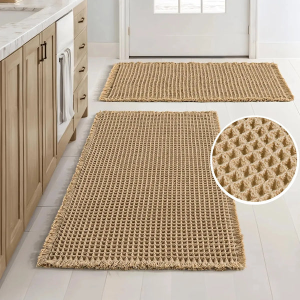 A rectangular beige waffle weave non-slip bathroom rug placed on a light wood floor.