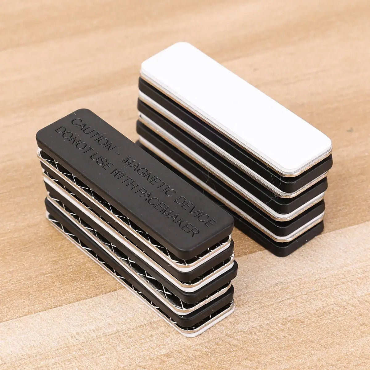 Stack of black and white magnetic curtain clips with strong adhesive backing