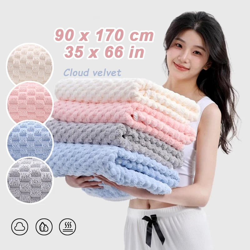A woman holds a stack of thickened microfiber bath towels in various pastel colors and textures.