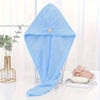 Light blue microfiber hair drying wrap towel draped on a glass stand with greenery in the background.