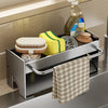 A stainless steel kitchen sink caddy holds sponges, dish tools, and a cloth on a countertop.