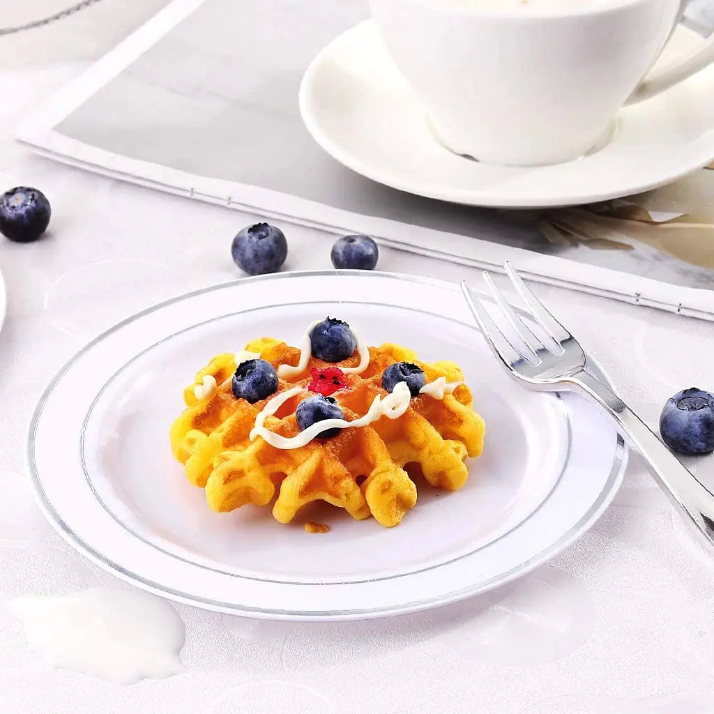 Eine Platte mit goldenen Waffeln, belegt mit Blaubeeren und einer Gabel, auf einem weißen Tisch.