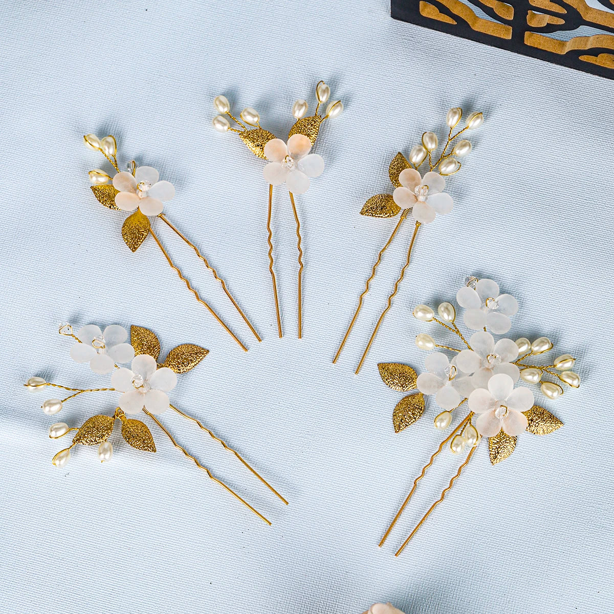 A set of pearl flower bridal hair clips featuring delicate white and gold floral designs on thin gold wires.