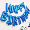 A silver and blue foil balloon banner spelling out Happy Birthday on a white wall.