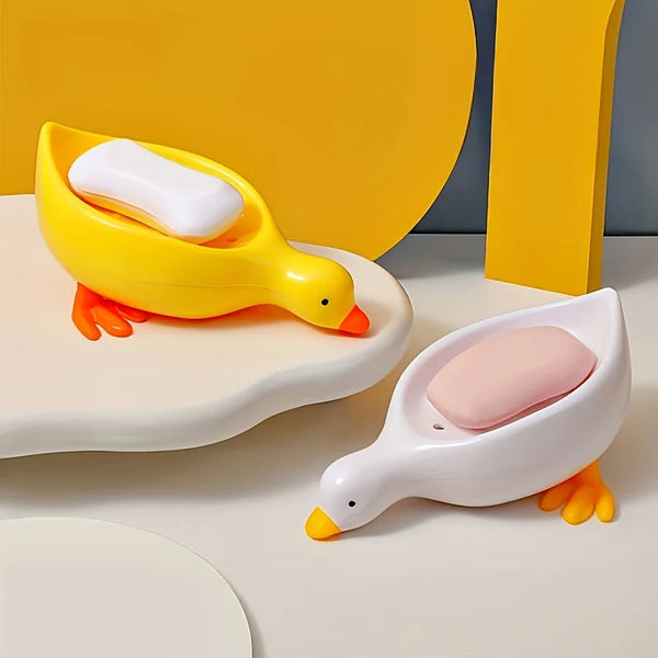 A yellow duck soap dish with a white bar of soap resting on a white tray.