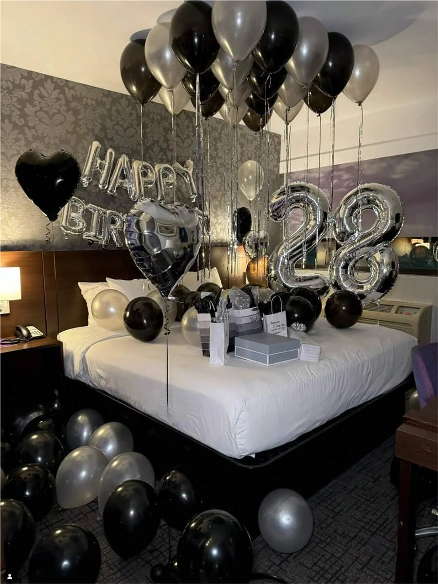Guirnalda de globos con números grandes plateados y negros de papel metálico decorando una habitación.