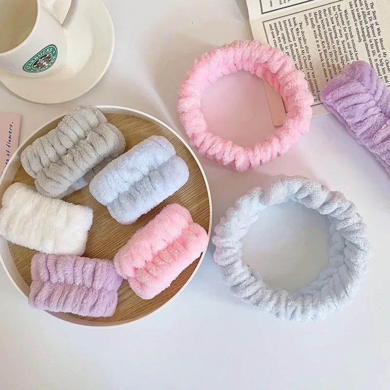 A collection of pink, purple, and white microfiber wrist sweatbands for face washing and skincare.