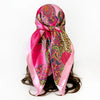 A vibrant pink scarf featuring a paisley print with leopard spots and colorful patterns tied around a dark hairstyle.