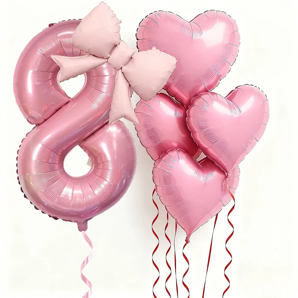 Un juego de seis globos de lámina en forma de corazón rosa que forman el número 8, atados con cintas rosas.