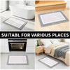 Various sizes of gray and white microfiber non-slip bath mats shown next to a bathtub and an oven.