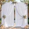Cortinas de tela plisada blanca enmarcando una entrada decorada con arreglos florales y velas.