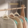 Five stainless steel non-slip hangers displaying various colored clothing items on a wooden rack.